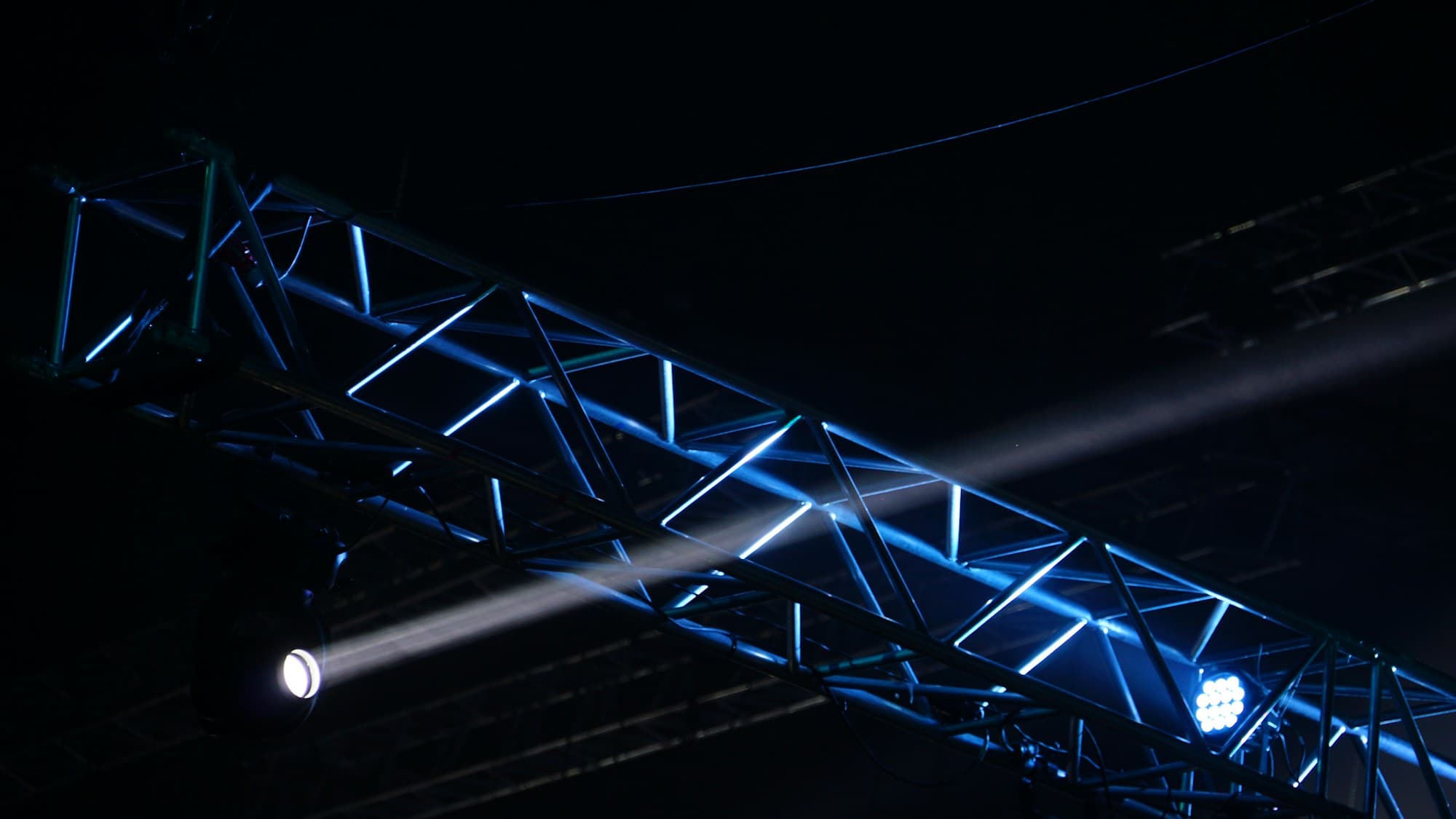 A steel lighting truss rises above an event stage
