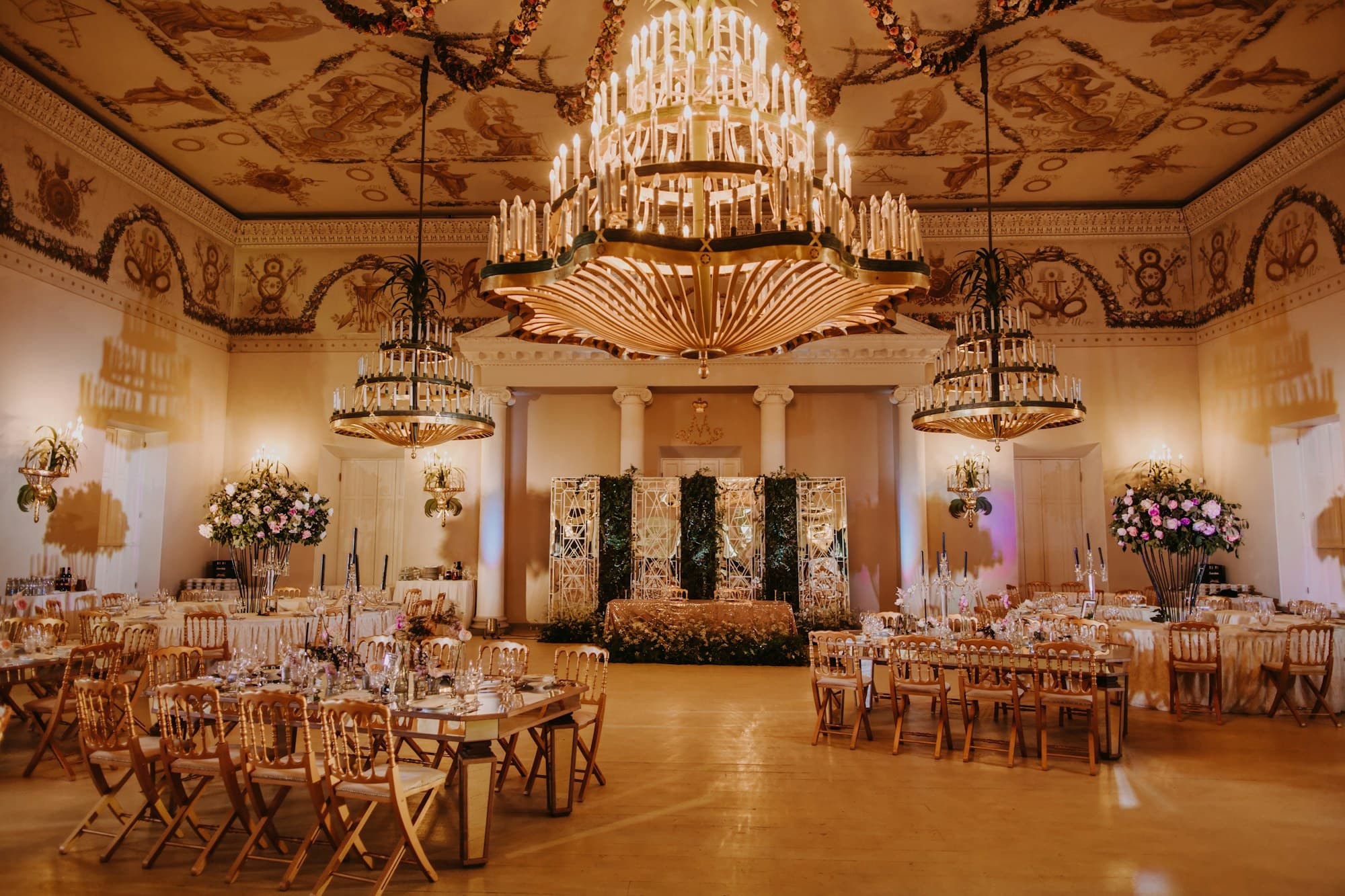 Banquet tables dressed for a luxury wedding beneath crystal chandeliers