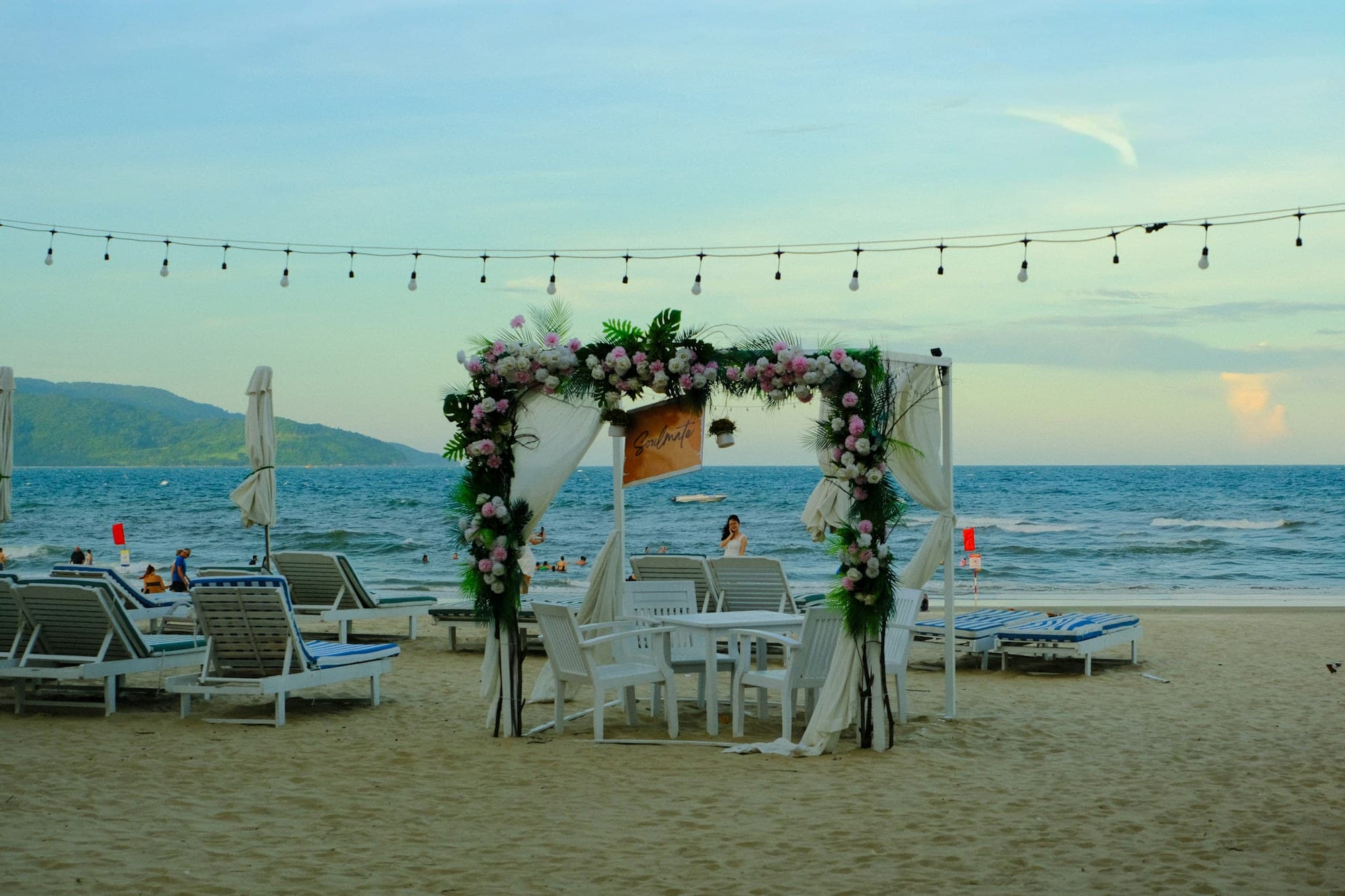 A floral wedding arch set on a sandy beach overlooking the ocean