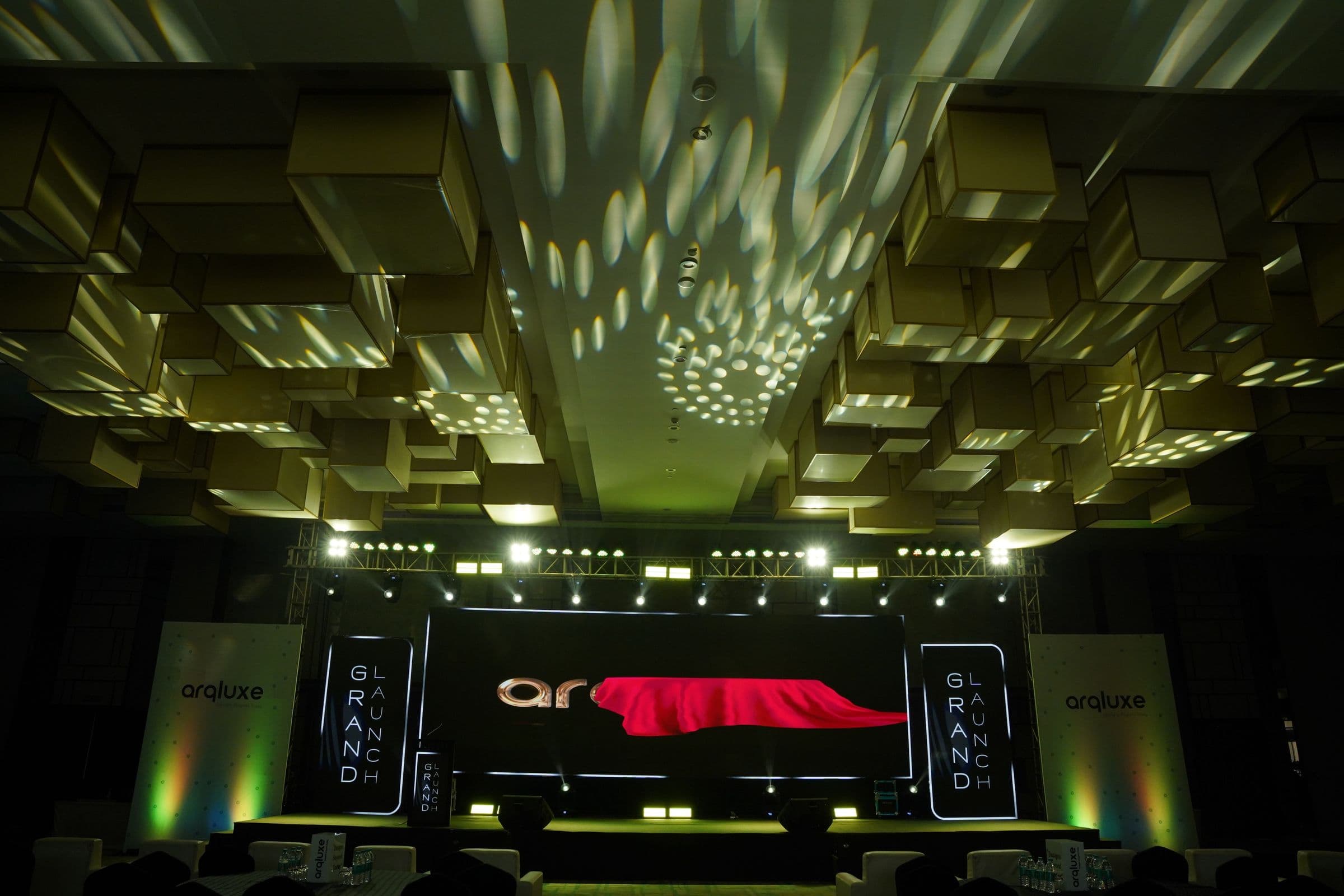 The Arqluxe launch hall with a red-lit stage and dappled ceiling lights