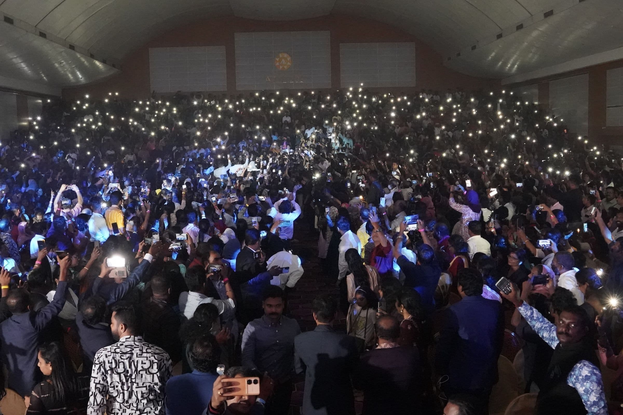 A full hall of students raising phone lights during Medical Victory Day