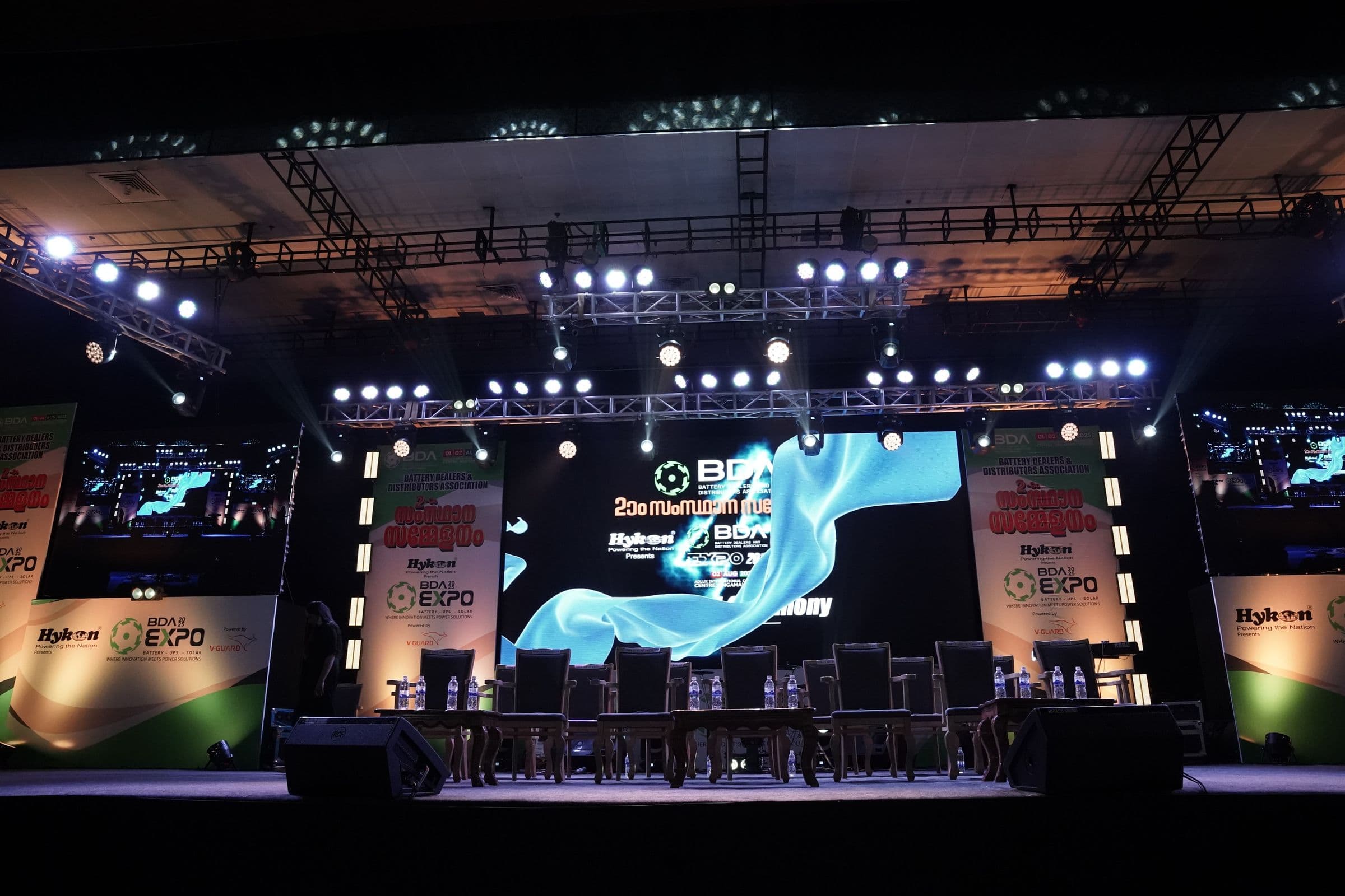 A stage with a wide LED screen and lighting rig at an XES exhibition