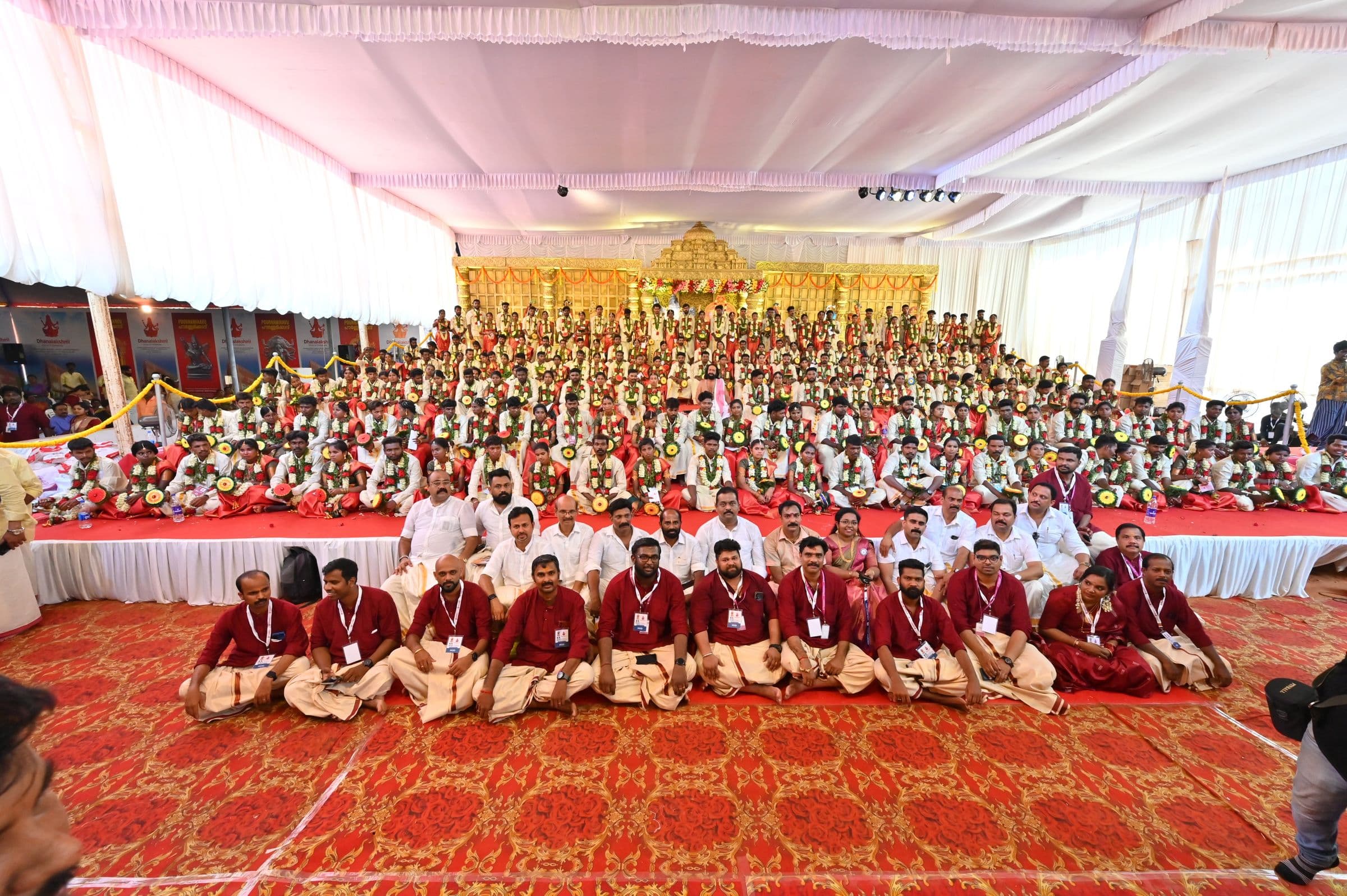 Hundreds of guests seated before a traditional decorated stage