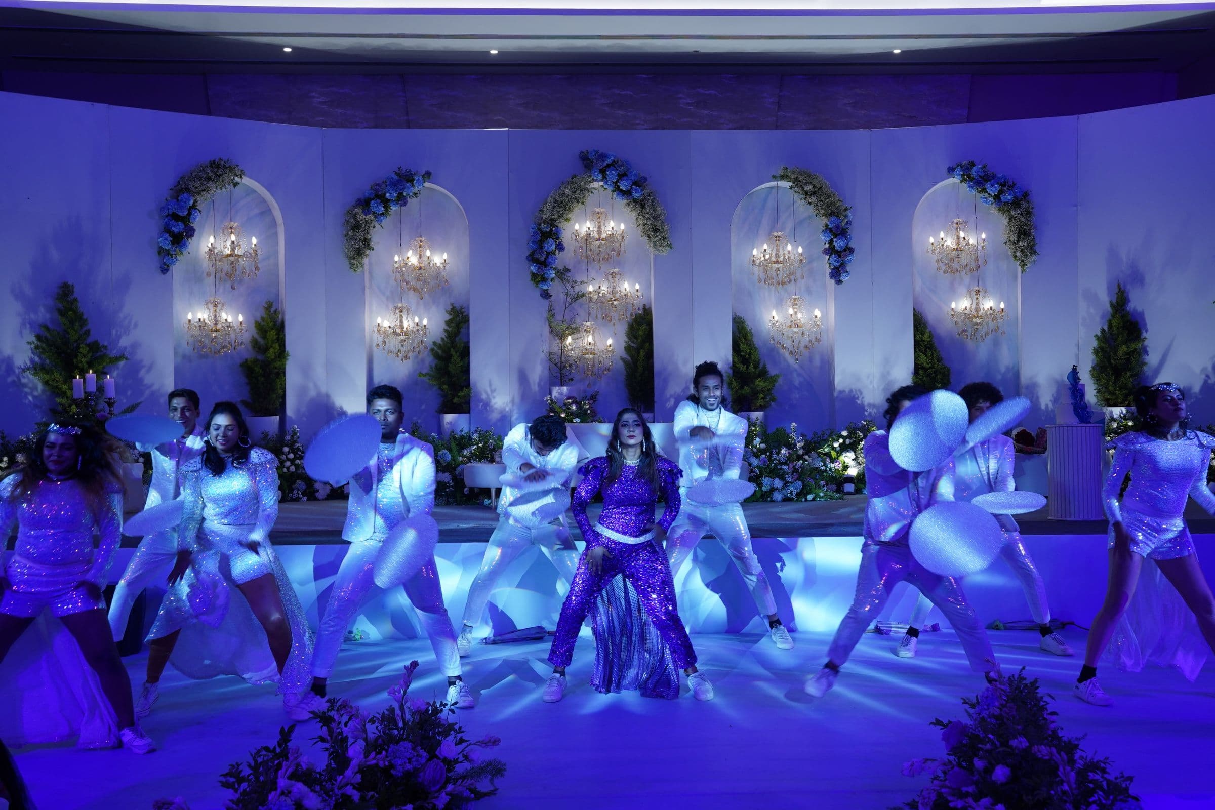 Performers dance on a blue-lit stage during a wedding celebration