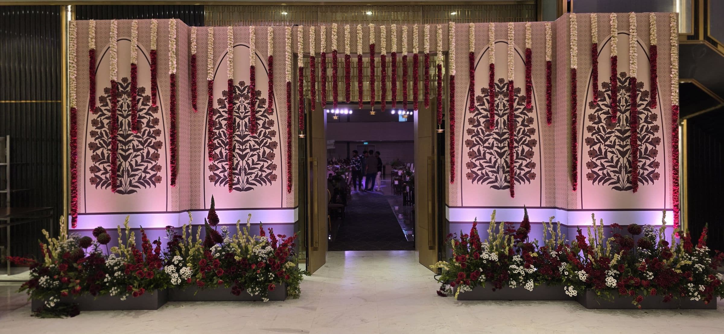A wedding entrance built with carved panels and floral arrangements