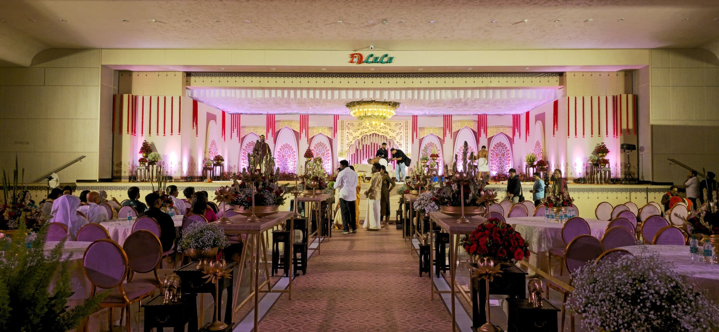 A wedding reception with dressed tables in front of a pastel floral stage