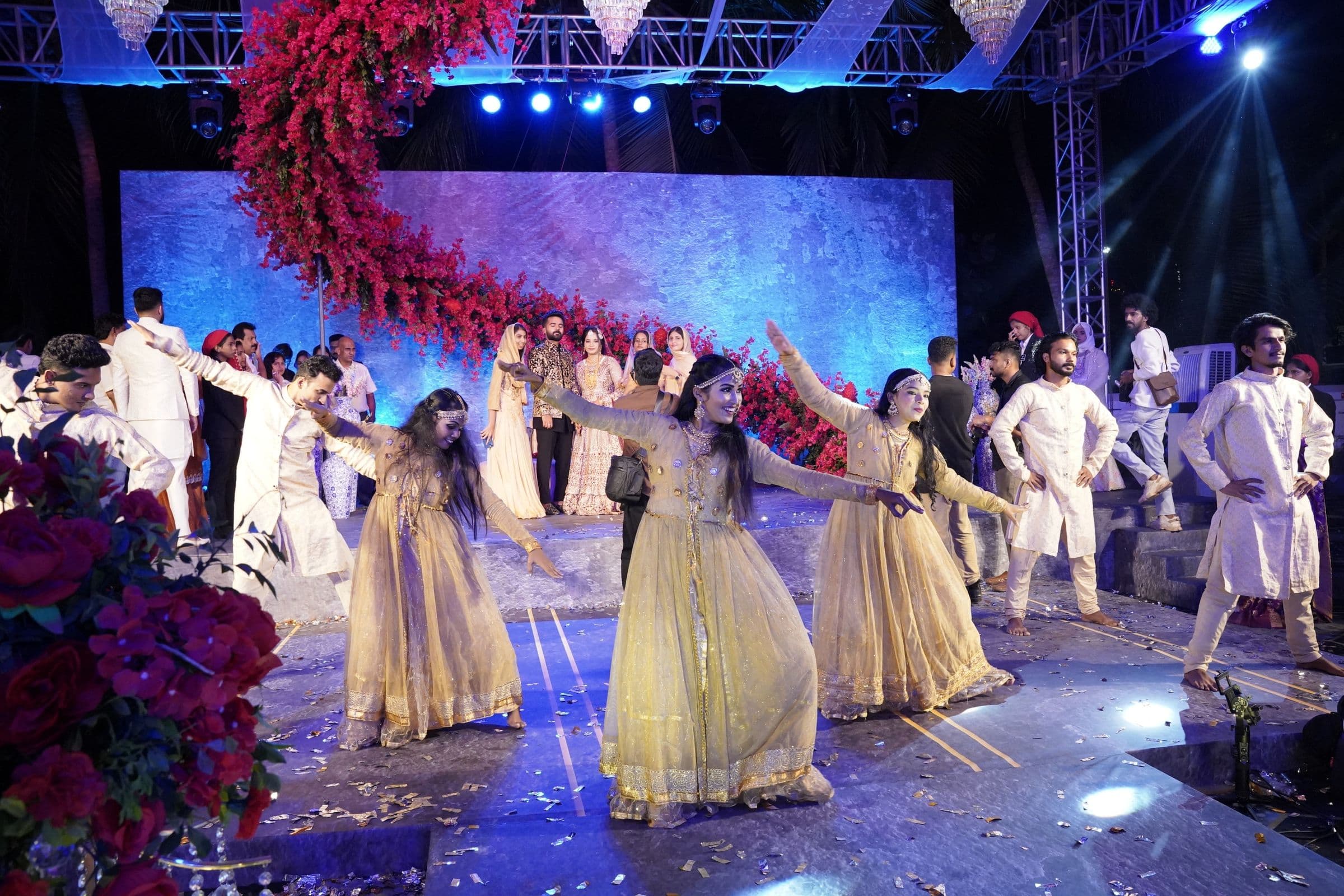 Guests dance on a floral stage at a wedding sangeet