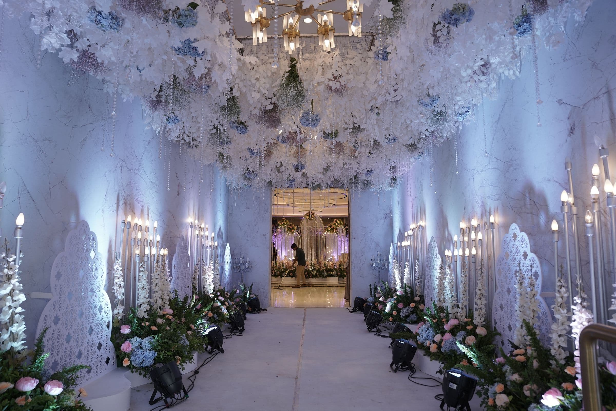 A white floral tunnel and chandeliers styled for a wedding entrance