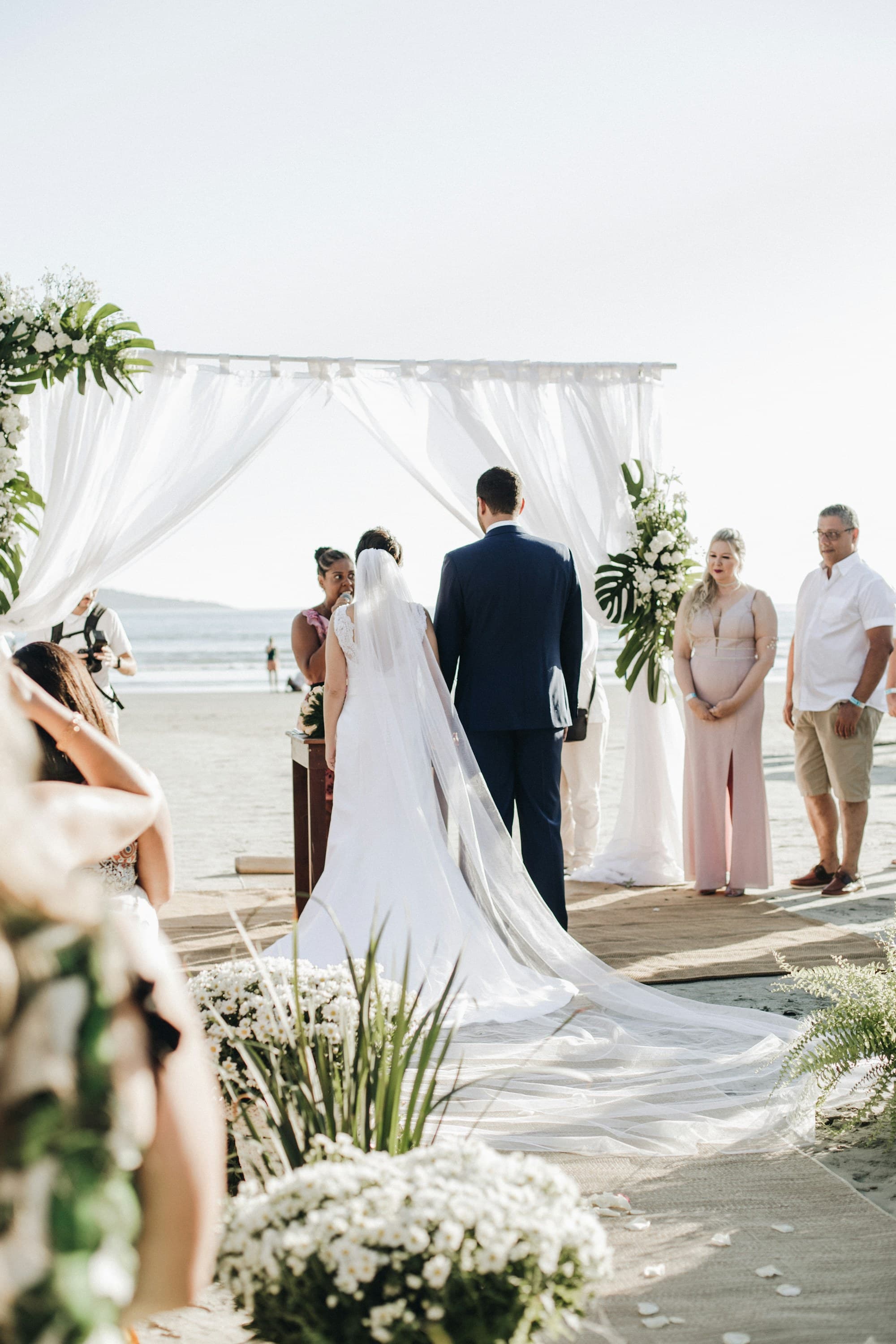 A newly married couple stand together on a shoreline at golden hour