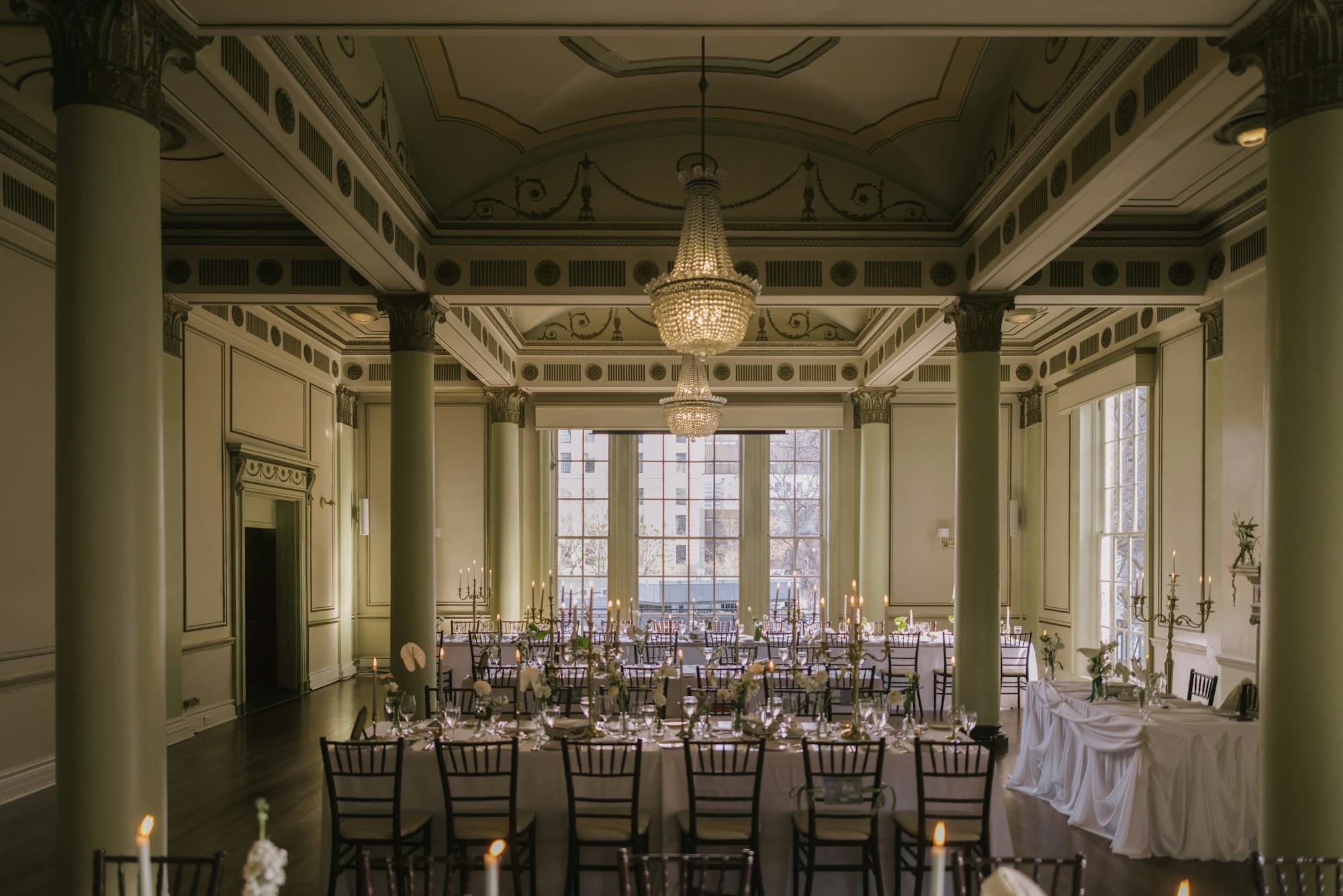A symmetrical wedding reception hall with long banquet tables and a grand chandelier